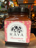 Jar of Raya Massaman Curry Paste on a metallic surface with a blurred indoor background.